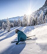 ein Skifahrer auf der frisch präparierten Piste bei Sonnenschein