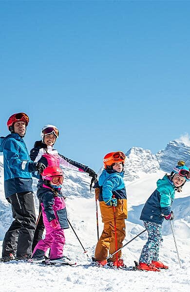 Eltern mit 2 Kindern auf Skiern vor dem Dachstein-Massiv